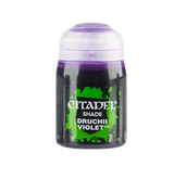 A small paint pot stands upright against a plain background, with a translucent white cap and a dark body bearing a bright green splatter label. The label reads “CITADEL,” “SHADE,” and “DRUCHII VIOLET.”