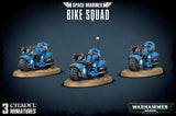 Three blue-armored Space Marine riders on futuristic motorcycles, each mounted on a round textured base, shown from front three-quarter angles against a dark background. The heading reads “SPACE MARINES BIKE SQUAD,” with “3 CITADEL MINIATURES” and “WARHAMMER 40,000” below.