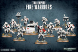 A squad of white-armored T’au Fire Warriors with red accents and rifles stands on round bases among a support turret and hovering drones against a dark blue textured background. The text reads “TAU EMPIRE FIRE WARRIORS” and “13 MINIATURES.”