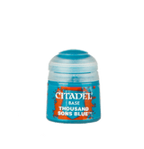 A small turquoise Citadel paint pot with a translucent pale blue cap, shown upright against a plain background. Its orange-and-blue label reads “CITADEL,” “BASE,” and “THOUSAND SONS BLUE.”