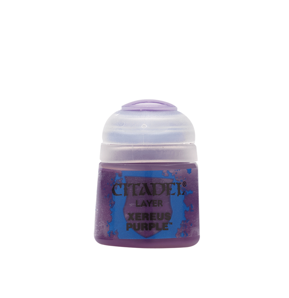 A squat purple Citadel paint pot stands centered against a solid green background, with a rounded pale lavender cap and a blue-and-purple splatter label. The label reads “CITADEL,” “LAYER,” and “XEREUS PURPLE.”