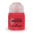 A squat bright red paint bottle stands upright with a wide translucent pale cap. Its front label shows a splatter graphic and the text “CITADEL COLOUR,” “AIR,” and “EVIL SUNZ SCARLET.”