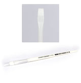 A white Citadel dry brush lies diagonally with its broad, flat white bristles under a clear protective cap at the handle end; an inset shows the bristle shape close up. The handle is printed with “CITADEL COLOUR” in black.
