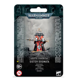 A packaged Adepta Sororitas miniature stands on a rocky base, wearing red and black armor and robes with a crown-like halo and holding a long staff. The black-and-gray backing reads “WARHAMMER 40,000” and “SISTER DOGMATA.”