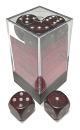 Dark red and black speckled six-sided dice with silver-colored pips are shown in a clear display box and as two loose dice in front. The box has a pink label with faint lettering that is not fully legible.