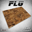 Rectangular gaming mat shown at an angle, printed with a mottled brown, rust-colored ground resembling junkyard terrain. The graphic includes the stylized text “FLG MATS” above and “6x4’ Junkyard” at the lower right.