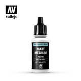 A small clear bottle with a black pointed cap and black label stands against a white background. The label has a turquoise stripe and reads “MATT MEDIUM,” with “70.540” below; the “AV vallejo” logo appears at upper left.