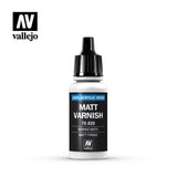 A small white bottle of Vallejo varnish stands upright against a white background, with a tall black ribbed cap and black label. The label reads “MATT VARNISH” and “100% ACRYLIC RESIN,” with Vallejo logos above and below.