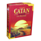 Red and yellow Catan board game extension box shown at an angle, with a large sunset over a green and golden landscape and three settlers on the front. The cover reads “CATAN,” “EXTENSION,” and “5-6 PLAYER.”