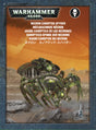 Front of a Warhammer 40,000 box featuring a black and metallic spider-like Necron miniature with bright green details against an orange desert scene. The packaging reads “WARHAMMER 40,000” and “NECRON CANOPTEK SPYDER.”