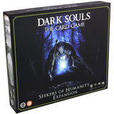 Dark Souls card game expansion box shown from the front and left side. The black cover has a blue-lit armored figure in a dark forest, thin green border, and the text “DARK SOULS THE CARD GAME” and “SEEKERS OF HUMANITY EXPANSION”; the side has pale monochrome artwork.