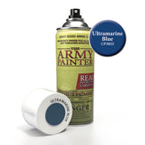 An upright spray primer can with a yellow-green label and black nozzle stands beside its white cap, which lies on its side showing a dark blue color swatch. The label reads “THE ARMY PAINTER,” and a blue circle reads “Ultramarine Blue CP3022.”