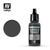 A dark gray Vallejo primer bottle with a black ribbed dropper cap stands beside a round dark gray color swatch on white. The label reads “SURFACE PRIMER,” “Dunkelgrau,” and “RAL7021.”