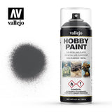 Vallejo Hobby Paint aerosol can with a clear cap, black-and-white label and miniature artwork, shown beside a sprayed dark gray paint swatch. The label reads “vallejo” and “HOBBY PAINT.”