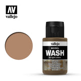 A dark brown Model Wash bottle with a ribbed black cap stands beside a round tan-brown color swatch on a white background. Its label reads “vallejo,” “MODEL WASH,” “for light colors,” and “Dark Brown.”