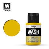 A small Vallejo Model Wash bottle with a black cap, yellow bands and a black-and-white label stands beside a round mustard-yellow color swatch. The label reads “vallejo,” “MODEL WASH” and “Dark Yellow.”