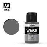 A grey wash bottle with a black cap stands beside a large circular grey color swatch. The label reads “vallejo,” “MODEL WASH” and “for grey & dark vehicles,” with the shade name Grey below.