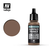 A small brown Vallejo primer bottle with a black dropper cap stands beside a round leather-brown color swatch. The black label reads “SURFACE PRIMER,” “70.626” and “Leather Brown,” with Vallejo logos above and below.
