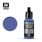 A small blue-violet primer bottle with a tall black cap stands beside a matching circular color swatch. Its black label reads “SURFACE PRIMER” and “Ultramarine,” with the “vallejo” logo above and below.