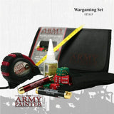 Wargaming set arranged before a black zip case: red-and-black tape measure, yellow measuring strip, two red and black gold-ended tools, red and green dice, and a glue bottle. Text reads “Wargaming Set” and “THE ARMY PAINTER.”