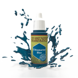 A bottle of Ultramarine Blue hobby paint with a white dropper cap stands amid glossy blue paint splashes against a black background. Its label reads “THE ARMY PAINTER,” “WARPAINTS,” and “Ultramarine Blue.”