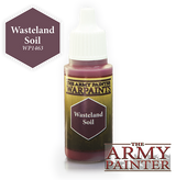 A small dropper bottle of Wasteland Soil paint stands upright, with a white ribbed cap, dark olive-and-gold label, and burgundy paint visible at the neck and base. The label reads “THE ARMY PAINTER WARPAINTS” and “Wasteland Soil”; a matching hexagon graphic reads “WP1463.”