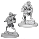 Two gray, unpainted Drow miniatures are shown separately on round bases with rocky terrain. One stands in a cloak with a weapon at his side; the other crouches with a crossbow held across his body.